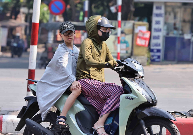 Mỗi khi phải ra đường, người lớn hay trẻ em đều dùng nhiều biện pháp để chống lại cái nắng nóng gay gắt. (Ảnh: Minh Đức/TTXVN) ttxvn-soc nhiet2.jpg