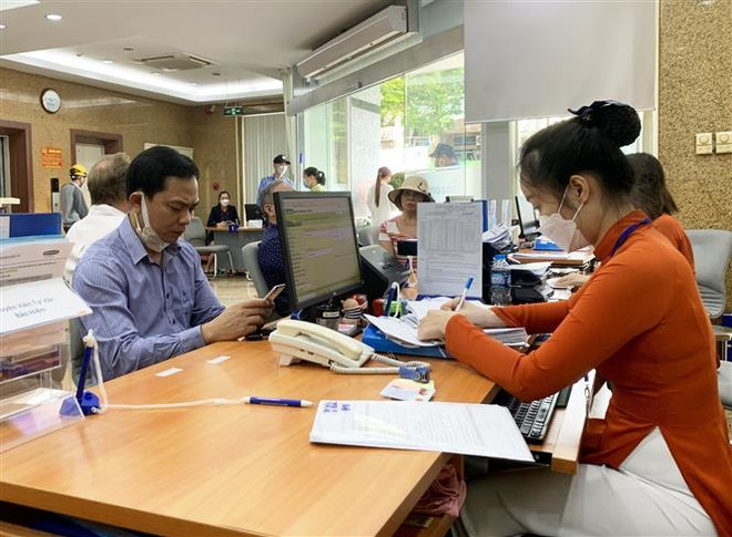 Khách hàng giao dịch tại ngân hàng Sacombank. (Ảnh: Hồng Đạt/TTXVN) Các ngân hàng liên tục đua lãi suất huy động, vượt 11%/năm ảnh 1