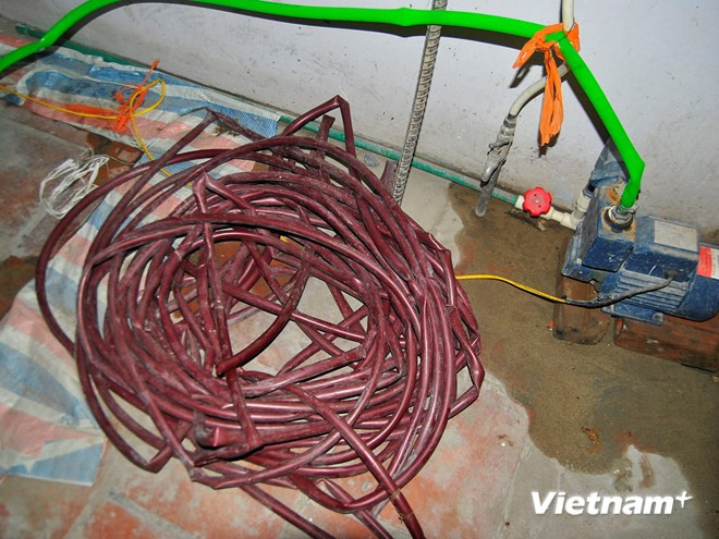 Mất nước, các hộ dân phải chuẩn bị ống dẫn để... bơm nhờ (Ảnh: Võ Phương/Vietnam+) Sẽ làm đường ống mới cho khu dân "khát" nước sạch giữa Hà Nội ảnh 2