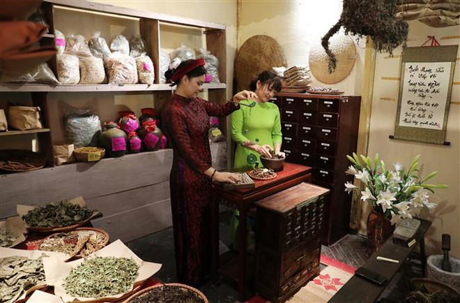Du khách trải nghiệm làm thầy lang tại khu trưng bày trong Hoàng thành Thăng Long. (Ảnh: Nhật Anh/TTXVN) Tái hiện Tết Đoan Ngọ truyền thống tại Hoàng thành Thăng Long ảnh 1