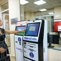 Người dân Hà Nội lấy số thứ tự xếp hàng làm thủ tục hành chính. (Ảnh: Tuấn Anh/TTXVN)