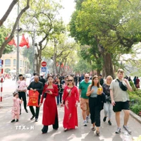 Du khách trong nước và quốc tế thảnh thơi du xuân bên hồ Hoàn Kiếm. (Ảnh: Phạm Kiên/TTXVN)