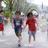 Các em nhỏ chơi đùa bên đài phun nước để tránh nóng tại Seoul, Hàn Quốc. (Ảnh: THX/TTXVN)