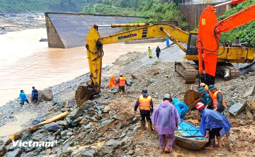 Phối hợp máy xúc và xuồng máy khẩn trương cứu hộ 2 người dân bị cô lập do nước lũ chia cắt. (Ảnh: PV/Vietnam+)