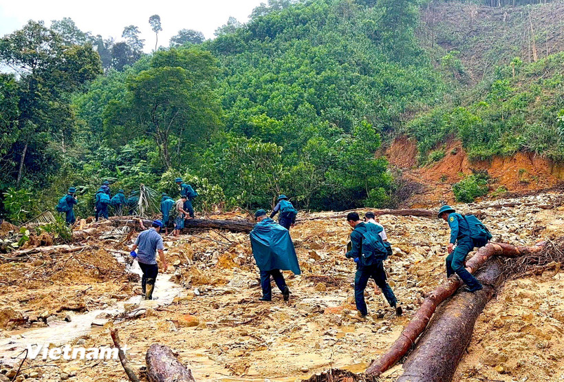 Bộ đội chi làm nhiều nhóm đi bộ vượt các điểm sạt lở, đường núi và sông suối gùi nhu yếu phẩm đến 14 hộ dân bị cô lập. (Ảnh: PV/Vietnam+)