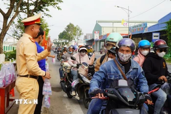 Những chai nước uống, những cái vẫy tay chào, những nụ cười… từ các tình nguyện viên của “Trạm dừng chân nghĩa tình” khiến nhiều người đi đường cảm thấy ấm lòng trên đường về quê. (Ảnh: Nhựt An/TTXVN)