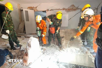 Đội công binh của đoàn Quân đội Nhân dân Việt Nam và lực lượng cứu hộ của Myanmar, UAE đục bê tông để mở lối xuống tiếp cận vị trí các nạn nhân bị vùi lấp. (Ảnh: TTXVN phát)