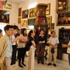 Khách tham quan lắng nghe giới thiệu về lịch sử tranh sơn mài tại cơ sở sản xuất sơn mài Định Hoà. (Ảnh: Khánh Ly/Vietnam+)