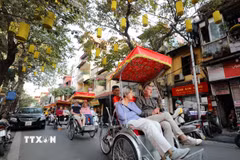 Du khách nước ngoài sử dụng xích lô thưởng ngoạn nét đẹp cổ kính của Phố cổ Hà Nội. (Ảnh: Thanh Tùng/TTXVN)