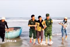 Lực lượng của Trạm Kiểm soát Biên phòng Roòn hỗ trợ đưa ngư dân bị nạn lên bờ. (Ảnh: TTXVN phát)