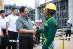 Thủ tướng Phạm Minh Chính với công nhân thi công dự án Cảng Hàng không Quốc tế Phú Quốc. (Ảnh: Dương Giang/TTXVN)