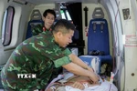 Bác sỹ Tổ Cấp cứu đường không, Bệnh viện Quân y 175 theo dõi, xử trí cho nạn nhân trên trực thăng. (Ảnh: TTXVN phát)
