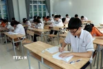 Các thí sinh ghi thông tin trên bài thi. (Ảnh: Nguyễn Lành/ TTXVN)