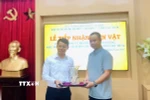 Phó Giám đốc Khu Di tích Chủ tịch Hồ Chí Minh tại Phủ Chủ tịch Nguyễn Văn Dương tiếp nhận lọ hoa do gia đình ông Vũ Thanh Tùng trao tặng. (Ảnh: Phương Lan/TTXVN)
