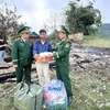 Cán bộ Đồn Biên phòng Ba Nang đến thăm hỏi, động viên và hỗ trợ bằng tiền mặt cùng các nhu yếu phẩm thiết yếu cho hộ dân bị cháy nhà. (Ảnh: TTXVN phát)