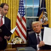 Tổng thống Mỹ Donald Trump (phải) ký sắc lệnh hành pháp ngay sau lễ nhậm chức, tại Nhà Trắng ở Washington DC., ngày 20/1/2025. (Ảnh: AP/TTXVN)