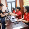 Các hộ dân đến nhận tiền thưởng do bàn giao mặt bằng sớm Dự án Cảng hàng không Quốc tế Gia Bình. (Ảnh: Thanh Thương/ TTXVN)