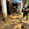 Lực lượng chức năng hỗ trợ người dân khắc phục hậu quả mưa lũ. (Ảnh: TTXVN phát)