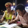 Lực lượng Cảnh sát giao thông trạm Đồng Phú lập biên bản, xử lý xe khách vi phạm giao thông. (Ảnh: Đậu Tất Thành/TTXVN)