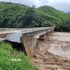 Nước sông Luồng dâng cao chảy xiết làm sập chân, mố cầu Sơn Thủy. (Ảnh: TTXVN phát)
