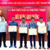 Lãnh đạo Ủy ban Nhân dân xã Phương Thiện trao giấy khen cho 5 công dân. (Ảnh: TTXVN phát)