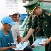 Cấp phát tài liệu chống khai thác IUU cho ngư dân. (Ảnh: Hồng Hiếu/TTXVN)