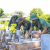 Chiến sỹ Bộ Chỉ huy Quân sự tỉnh Điện Biên tỉ mỉ hoàn thiện công đoạn trát vữa, cố định các hạng mục phần mộ sau khi lấy mẫu sinh phẩm xác định danh tính hài cốt liệt sỹ. (Ảnh: Xuân Tư/TTXVN)