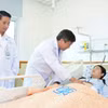 Bác sỹ Bệnh viện Đại học Y dược Thành phố Hồ Chí Minh thăm khám cho bệnh nhân 18 tuổi bị ung thư dạ dày giai đoạn tiến xa. (Ảnh: TTXVN phát)