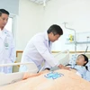 Bác sỹ Bệnh viện Đại học Y dược Thành phố Hồ Chí Minh thăm khám cho bệnh nhân 18 tuổi bị ung thư dạ dày giai đoạn tiến xa. (Ảnh: TTXVN phát)
