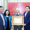 Trưởng Ban Tuyên giáo Trung ương Nguyễn Trọng Nghĩa trao Huy hiệu 65 năm tuổi Đảng cho ông Lê Xuân Tùng. (Ảnh: Phương Hoa/TTXVN)
