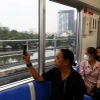 Người dân lưu lại hình ảnh đô thị bên ngoài khi trải nghiệm tuyến metro số 1. (Ảnh: Huyền Trinh/TTXVN)