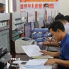 Chuyên viên lĩnh vực xây dựng, giao thông, công thương phường Thiên Hương kiểm tra thông tin hồ sơ công dân nộp. (Ảnh: Minh Thu/TTXVN)