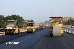 Nhà thầu huy động máy móc, nhân lực để thảm những mét bê tông nhựa cuối cùng để thi công tiếp hệ thống an toàn giao thông. (Ảnh: Khánh Hùng/Vietnam+)