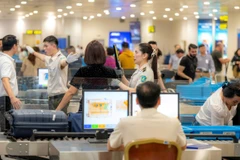 Nhân viên an ninh hàng không tại Sân bay Quốc tế Nội Bài kiểm tra hành khách qua cửa soi chiếu. (Ảnh: PV/Vietnam+)