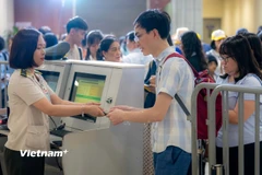 Nhân viên an ninh hàng không kiểm tra giấy tờ hành khách làm thủ tục đi máy bay tại Cảng Hàng không quốc tế Nội Bài. (Ảnh: PV/Vietnam+)