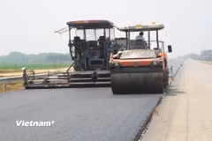 Nhà thầu thi công thảm bê tông nhựa một dự án đường bộ. (Ảnh: Việt Hùng/Vietnam+)