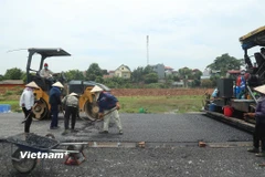 Nhà thầu thi công thảm nhựa nền đường một dự án đường bộ cao tốc. (Ảnh: Việt Hùng/Vietnam+)