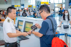 Nhân viên an ninh hàng không kiểm tra giấy tờ hành khách làm thủ tục lên máy bay. (Ảnh: PV/Vietnam+)
