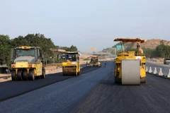 Nhà thầu huy động máy móc, nhân lực để thảm những mét bê tông nhựa trên đoạn tuyến cao tốc. (Ảnh: Việt Hùng/Vietnam+)