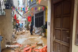 Bùn đất phun trào lên cống và được các lực lượng chức năng xử lý hút, thu dọn. (Ảnh: Minh Hiếu/Vietnam+) 