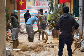 Người dân và công nhân được huy động nhằm khắc phục sự cố tràn bùn. (Ảnh: Minh Hiếu/Vietnam+)