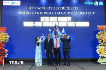 Anh Hùng lao động Hồ Quang Cua cùng các con nâng cao cúp "Gạo ngon nhất thế giới" năm 2025 tại buổi lễ. (Ảnh: Nguyễn Văn Việt/TTXVN)