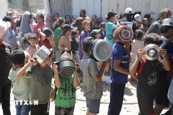 Trẻ em xếp hàng nhận thức ăn cứu trợ tại trại tị nạn Jabalia ở Dải Gaza. (Ảnh: THX/TTXVN)