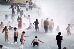 Người dân tránh nóng tại đài phun nước ở Paris, Pháp. (Ảnh: THX/TTXVN)