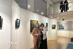 Họa sỹ Liên Phạm (bên phải) chia sẻ cảm xúc vui mừng với bạn bè Pháp tại Triển lãm. (Ảnh: Ngọc Hiệp/TTXVN)