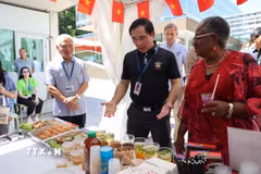 Tham tán Công sứ Phạm Quang Huy (áo đen) giới thiệu gian hàng của Việt Nam với Tổng Giám đốc WTO Ngozi Okonjo-Iweala. (Ảnh: Anh Hiển/TTXVN)
