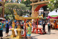 Trẻ nhỏ lấy nước tắm Phật xoa lên đầu người lớn để cầu chúc gặp nhiều may mắn trong dịp Tết cổ truyền Bun Pi May của Lào. (Ảnh: Xuân Tú/TTXVN)