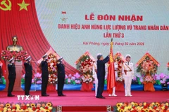 Tổng Bí thư Tô Lâm, Bí thư Quân ủy Trung gắn Huy hiệu Anh hùng Lực lượng Vũ trang nhân dân lên Quân kỳ Quyết thắng của Quân chủng Hải quân. (Ảnh: Trọng Đức/TTXVN)