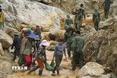 Người dân cùng các cán bộ, chiến sỹ Quân đoàn 34 triển khai công tác mở đường vào 5 thôn ở xã Ngọc Linh (Quảng Ngãi) bị cô lập do mưa lũ. (Ảnh: Dư Toán/TTXVN)