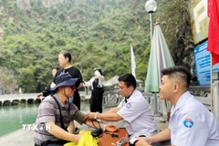 Nhân viên y tế tư vấn, kiểm tra sức khỏe cho du khách nước ngoài tại điểm trực y tế thường trực trên vịnh Hạ Long. (Ảnh: TTXVN phát)